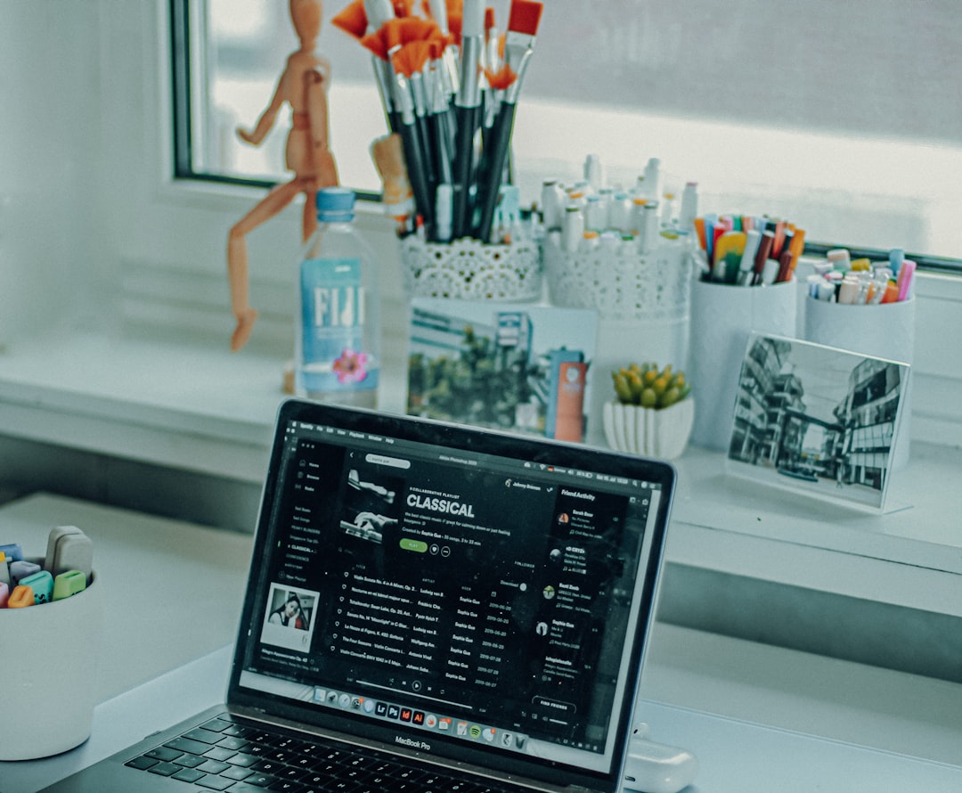 MacBook Pro in front of desk set stationery with classical music playlist on Spotify